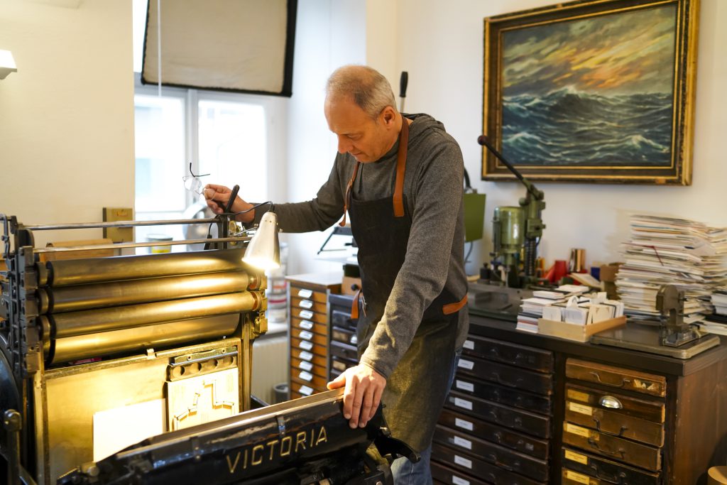 Alfred Pfeifer an der antiken Buchdruckmaschine Victoria-Tiegeldruckpresse