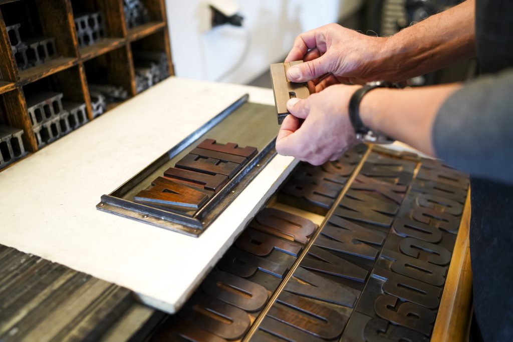 Buchdrucker Alfred Pfeifer beim Hantieren mit Holzlettern